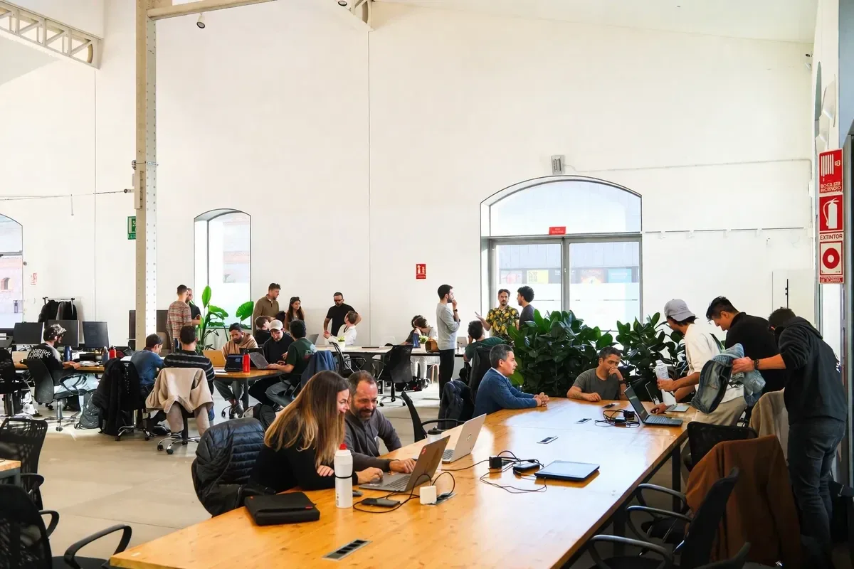 People working at long shared tables inside Mad Tech Campus